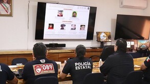 Personas de espaldas mirando a una pantalla donde se proyectan imágenes de seis personas.
