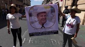 dos mujeres protestantes sostienen una pancarta con la foto de carlos manzo