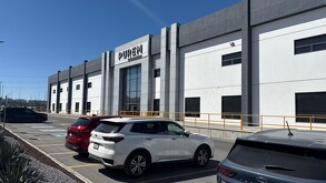 La empresa PUREM  se ubica en el Parque Industrial Santa María, en Ramos Arizpe; hay algunos vehículos en el estacionamiento.