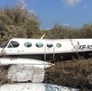 Una avioneta bimotor Cessna blanca con la matrícula XB-NSI parcialmente destruida y estrellada entre la densa maleza y arbustos, con un accidente
