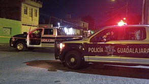 Patrullas y elementos de la Policía de Guadalajara junto a una cinta policiaca que acordona el perímetro de la escena del crimen con casas alrededor