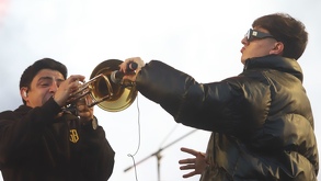 Hombre con gafas y chamarra pone un micrófono junto a un músico.