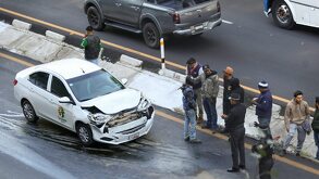 Un vehículo blanco accidentado, y al lado un conjunto de personas que observan el accidente.