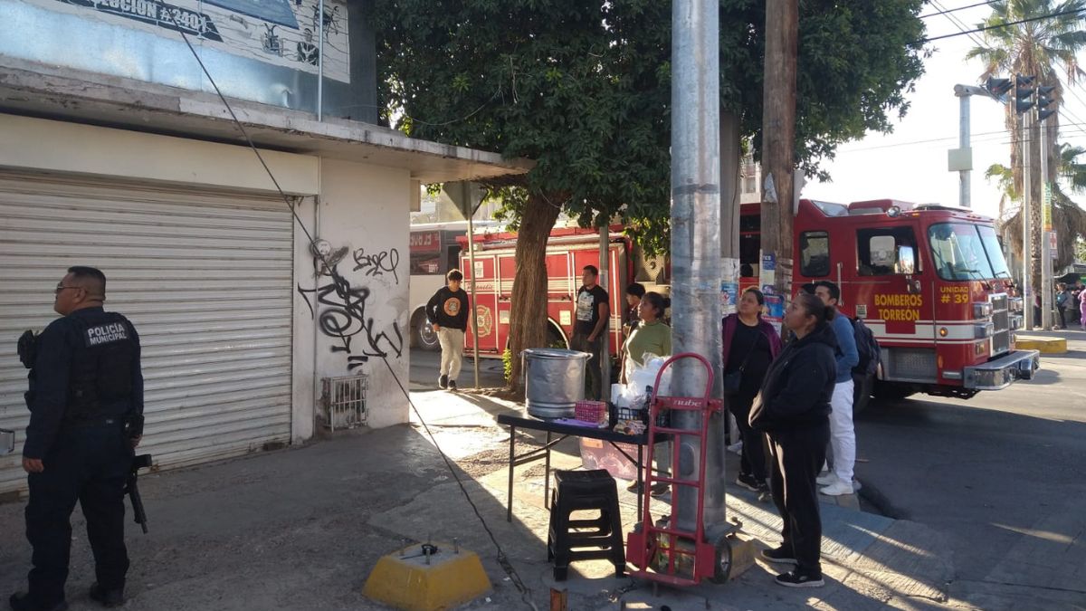 Personas observando la una casa en donde un hombre intentó quitarse la vida, al fondo se puede ver un camión de bomberos.