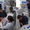 Dos personas de la tercera edad y una mujer platicando en una farmacia