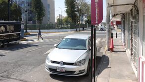 Auto blanco estacionado en zona de parquímetros frente a un hospital en Puebla.
