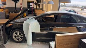 Carro negro termina dentro de un estamblecimiento de comida, con partes del cristal con el que se impactó.