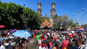 Gente caminando al aire libre hacia la Iglesia de San Judas Tadeo en la Ciudad de México.