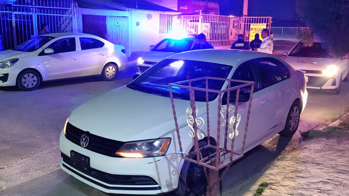 Carro blanco estacionado tras haber chocado, además se ven elementos de Peritos de Torreón y algunos vecinos de la zona.