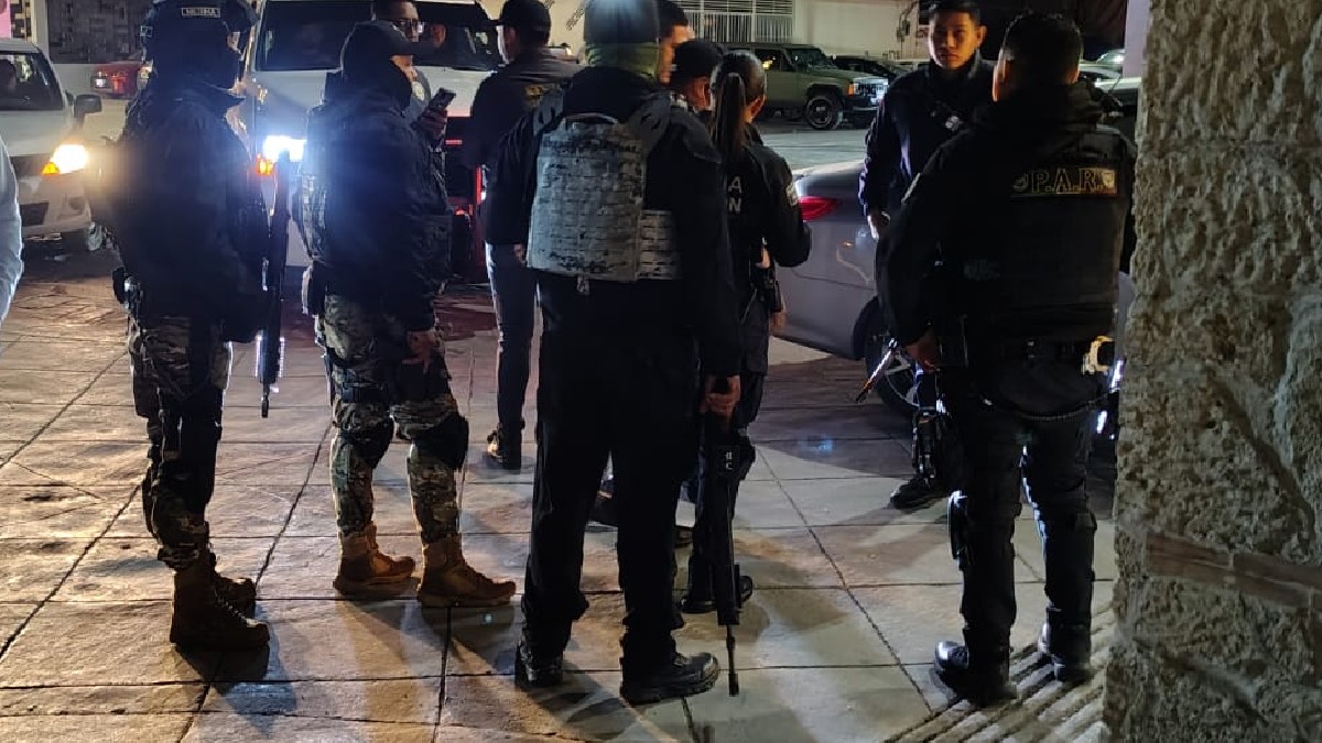 Elementos de policía con uniformes en color negro y pistolas en la mano