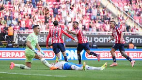 Jugadores de Chivas festejando un gol de la 'Hormiga' González, con los jugadores de Rayados tendido en el piso.