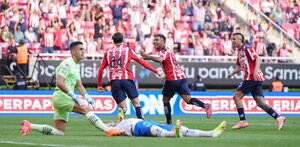 Jugadores de Chivas festejando un gol de la 'Hormiga' González, con los jugadores de Rayados tendido en el piso.