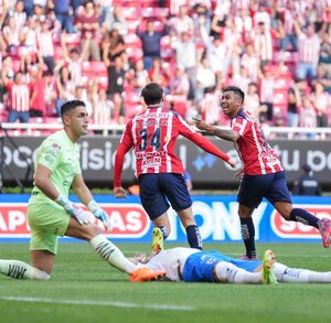 Jugadores de Chivas festejando un gol de la 'Hormiga' González, con los jugadores de Rayados tendido en el piso.