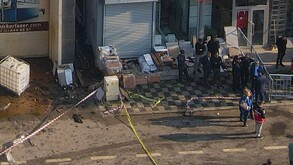 Varias personas al lado de cajas de cartón quemadas rodeadas de cintas amarillas de prohibido