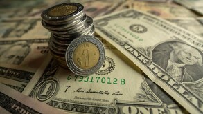 Montaña de pesos mexicanos sobre billetes de dólares estadounidenses.