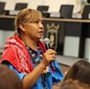 Alma López, mujer wixárika en el Centro Integral de Servicios Zapopan sosteniendo un micrófono con personas alrededor.