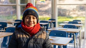 Aula vacía y un niño abrigado por las condiciones climáticas que se esperan por el  frente frío número 13 en Puebla.
