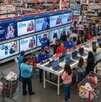Gente comprando algunos electrodomésticos y también hay otras personas viendo unas lap tops que se venden con descuentos en una tienda departamental.