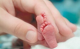 planta de pies de bebé con una mano tocándolos