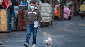 Mujer paseando su perro con cubrebocas por mala calidad del aire.