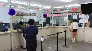 Una oficina gubernamental o de atención con varias estaciones de servicio. Muestra ciudadanos y empleados interactuando en el interior de una sala amplia en Tla