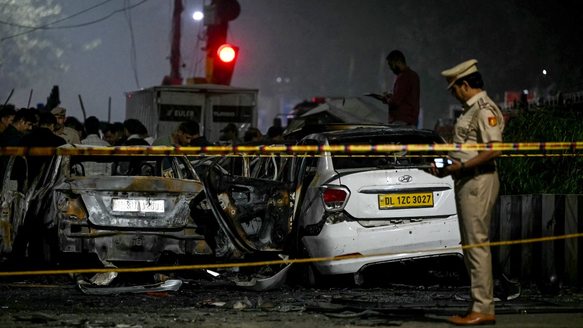 Automóviles quemados y un oficial observando la escena.
