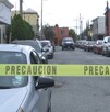 Hay carros estacionados y una cinta de precaución amarilla, además al fondo se encuentra una patrulla.