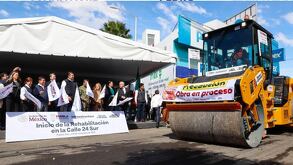 personas con banderines frenta a una maquina en el inicio de una obra de repavimentación en puebla