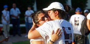 Madres y familiares de personas desaparecidas en jalisco dándose un abrazo vistiendo playeras con fichas de búsqueda en medio de la calle