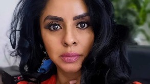 Mujer delgada y maquillada, con cabello ondulado oscuro.