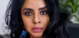 Mujer delgada y maquillada, con cabello ondulado oscuro.