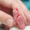 planta de pies de bebé con una mano tocándolos