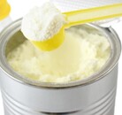 Biberón y frasco con fórmula para bebé en color amarillo con cucharon del mismo color