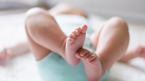 Se observan unos pies de bebé, no se le ve el rostro al menor, sólo que está acostado.