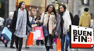 Tres mujeres sonriendo con bolsas de compras en las manos usando abrigos y bufandas y caminando por las calles con personas y tiendas de fondo