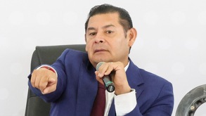 Hombre con un micrófono en la mano señalando hacia el público.