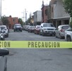 Hay carros estacionados y una cinta de precaución amarilla, además al fondo se encuentra una patrulla.