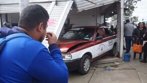 Un taxi chocado se estampa contra un puesto a la orilla de carretera.