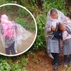 Niños con uniforme escolar se cubren de la lluvia con plásticos.