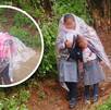 Niños con uniforme escolar se cubren de la lluvia con plásticos.