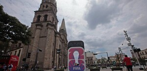 Una gran pantalla digital frente a la Catedral de Guadalajara y un templo en el centro histórico, muestra el logo del Mundial 2026 de la FIFA con el lema 