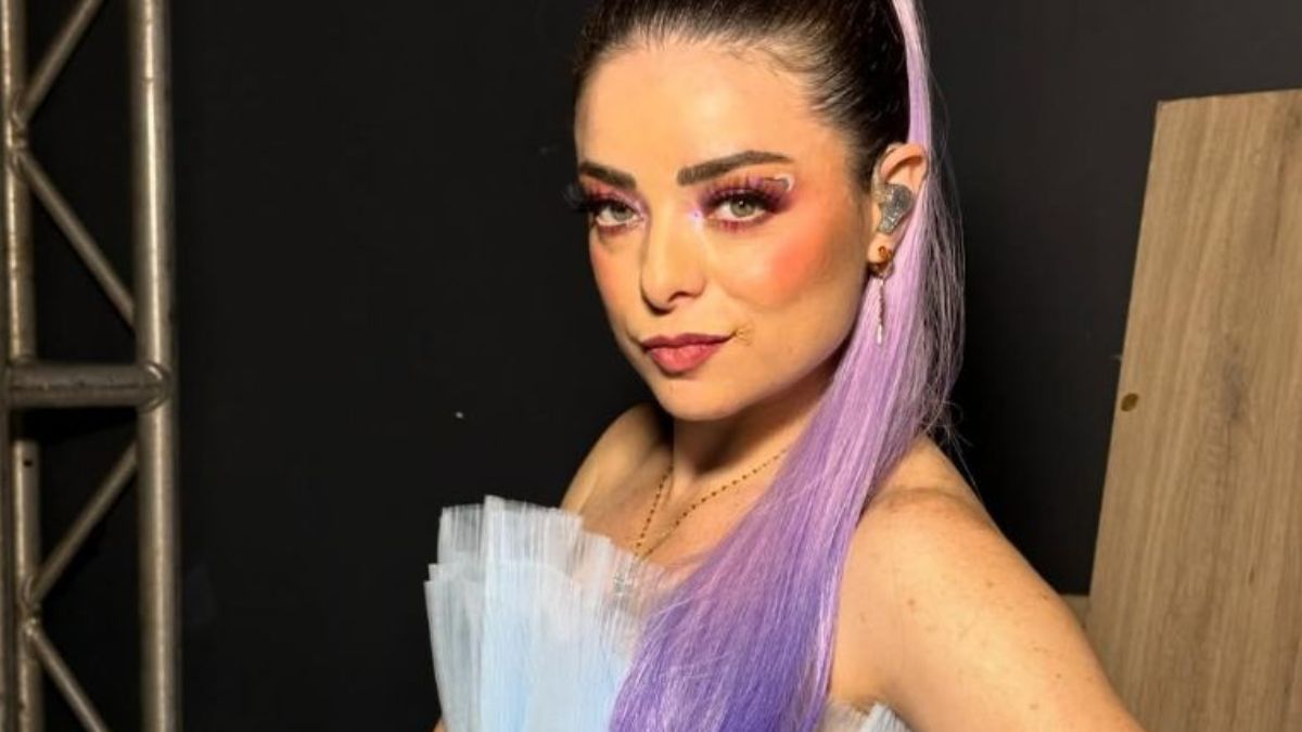 Violeta Isfel aparece con una coleta y cabello color morado, además de un apuntador , al parecer la imagen es de una de sus presentaciones.