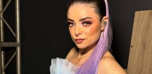 Violeta Isfel aparece con una coleta y cabello color morado, además de un apuntador , al parecer la imagen es de una de sus presentaciones.