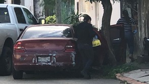 Un vhículo rojo se estralla con un árbol, junto a una mujer en la puerta de copiloto.