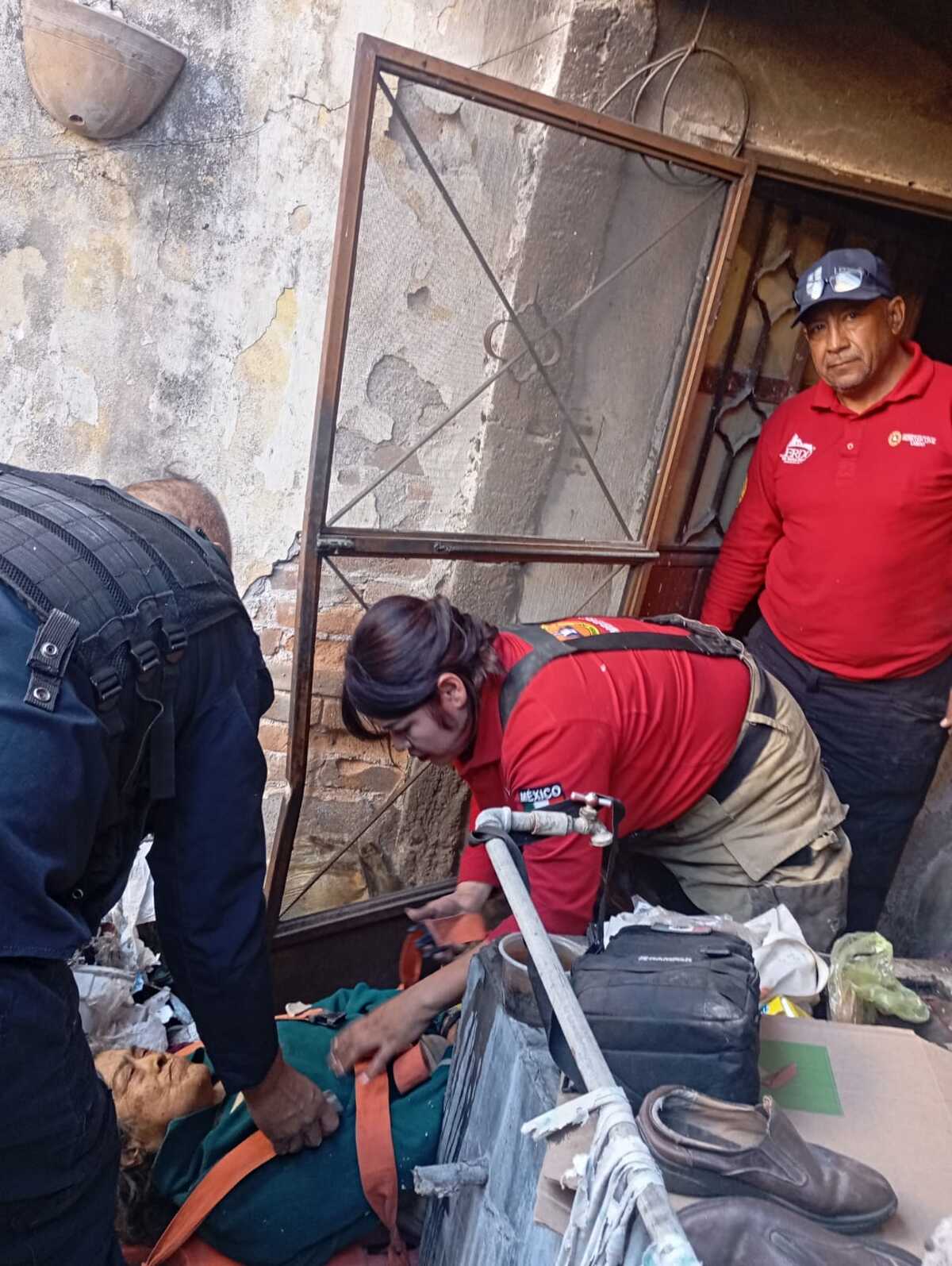 Mujer de 84 años siendo atendida por paramédicos de la Cruz Roja, tras caer y quedar atrapada en su casa en Lerdo.