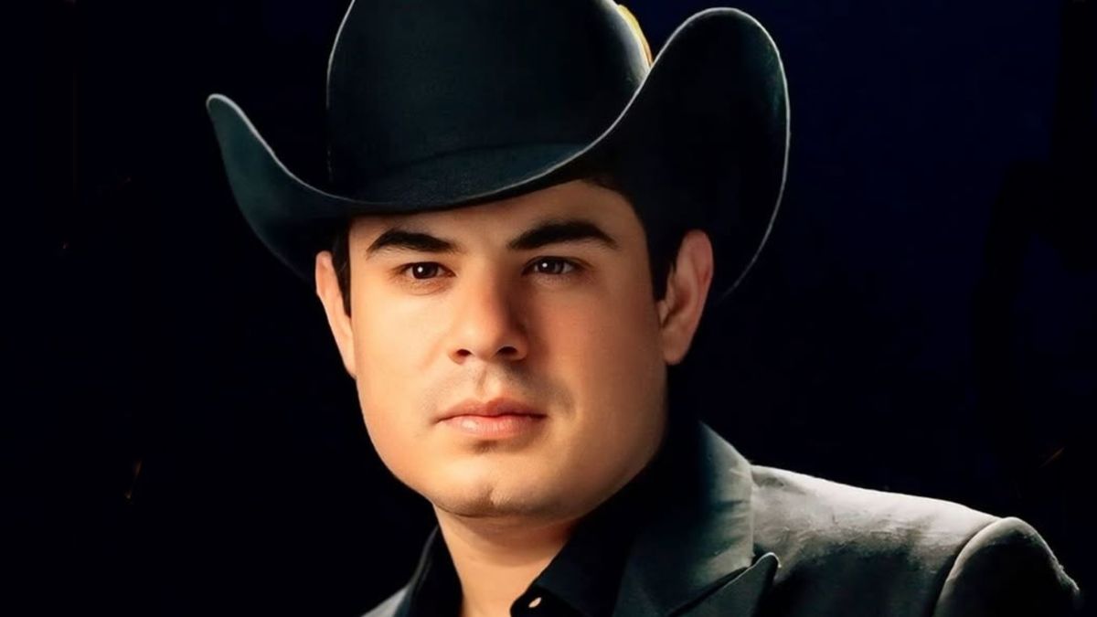 Alfredito Olivas con sombrero negro y saco negro, posando para la foto.