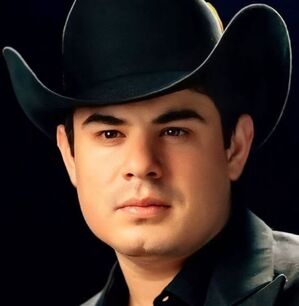 Alfredito Olivas con sombrero negro y saco negro, posando para la foto.