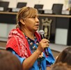 Alma López, mujer wixárika en el Centro Integral de Servicios Zapopan sosteniendo un micrófono con personas alrededor.