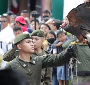 Águila sobre cadete uniformado y personas de fondo
