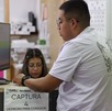 Hombre parado frente a una computadora mientras responde su examen teórico para tramitar la licencia de conducir en Puebla.